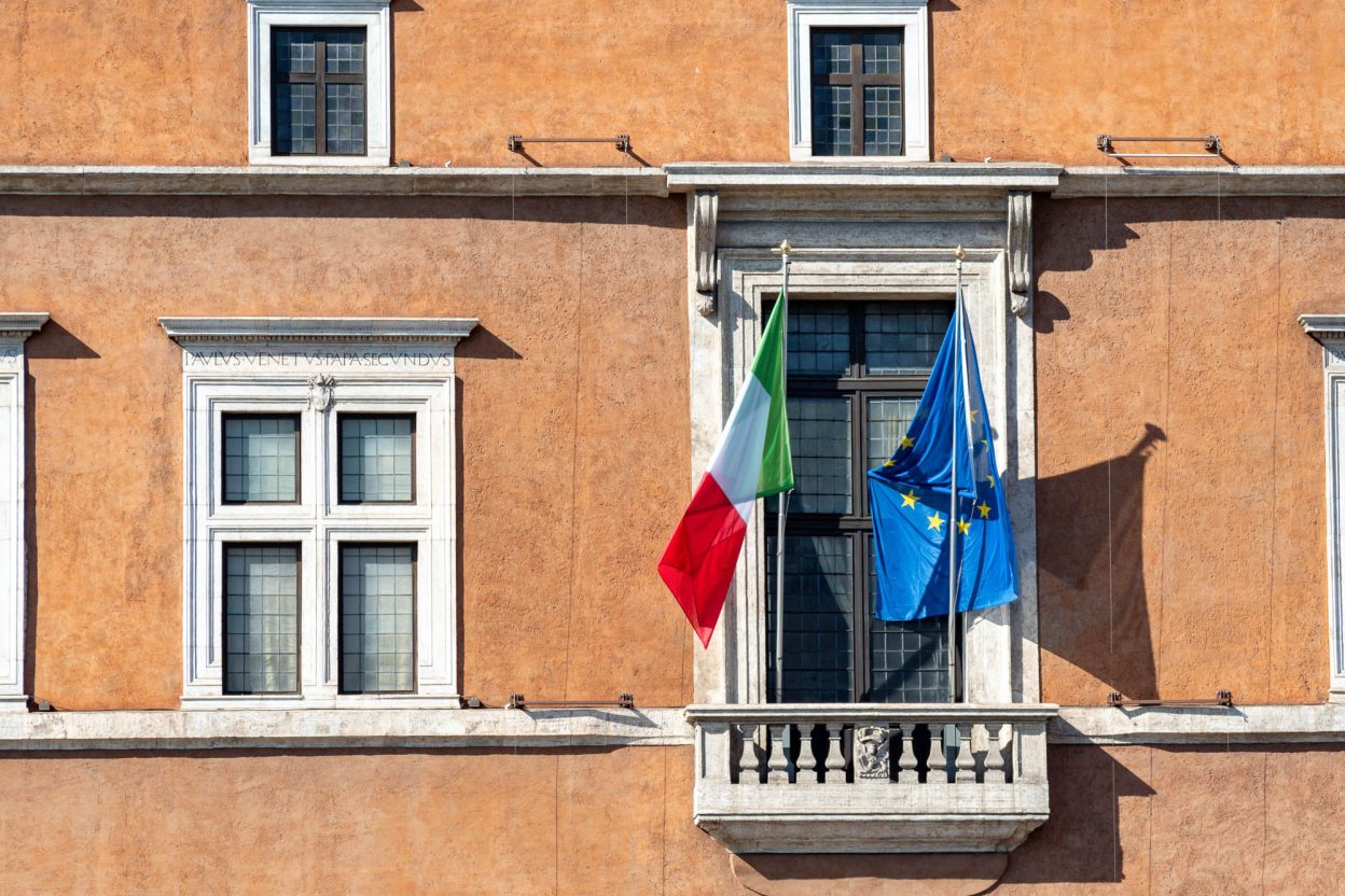 close up of a window with an italian and eu flag flying out front