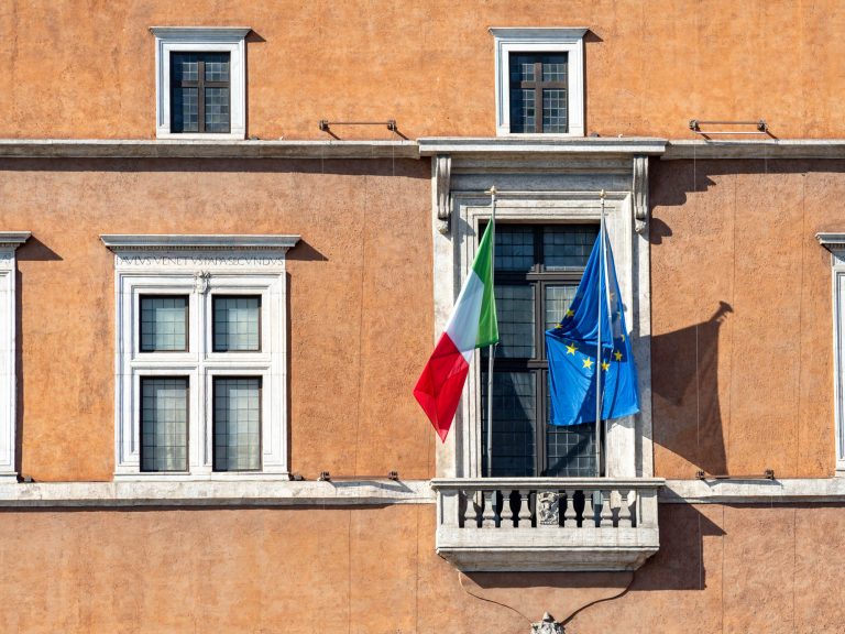 close up of a window with an italian and eu flag flying out front