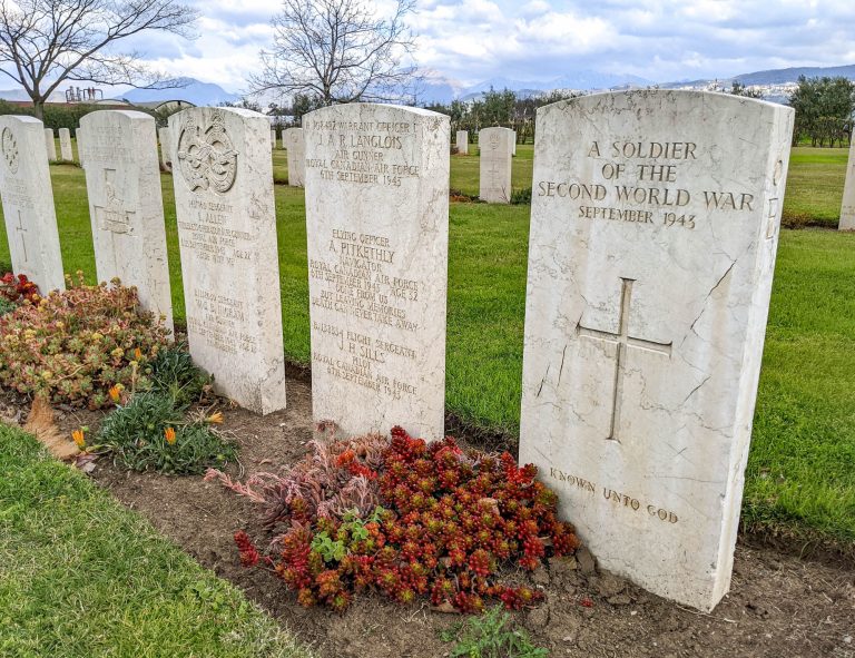 headstones with red flowers in front at salerno war cemetery