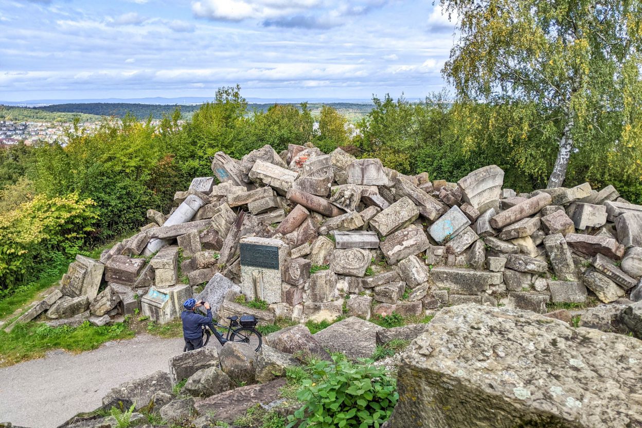 Tall stack of rubble with a man on a bike taking a picture of it
