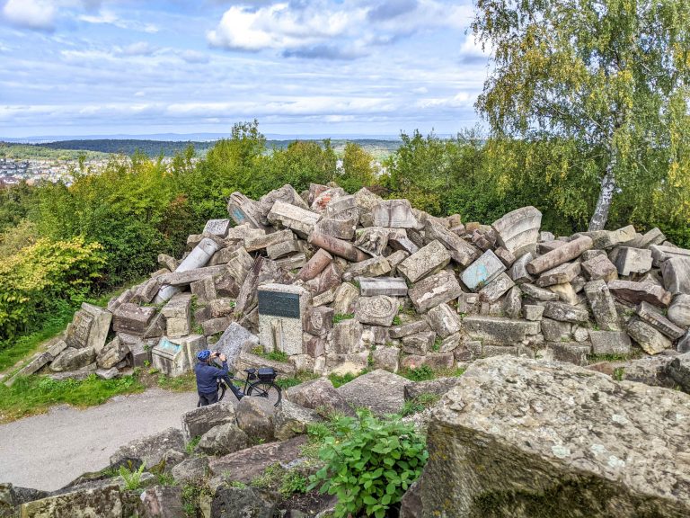 Tall stack of rubble with a man on a bike taking a picture of it