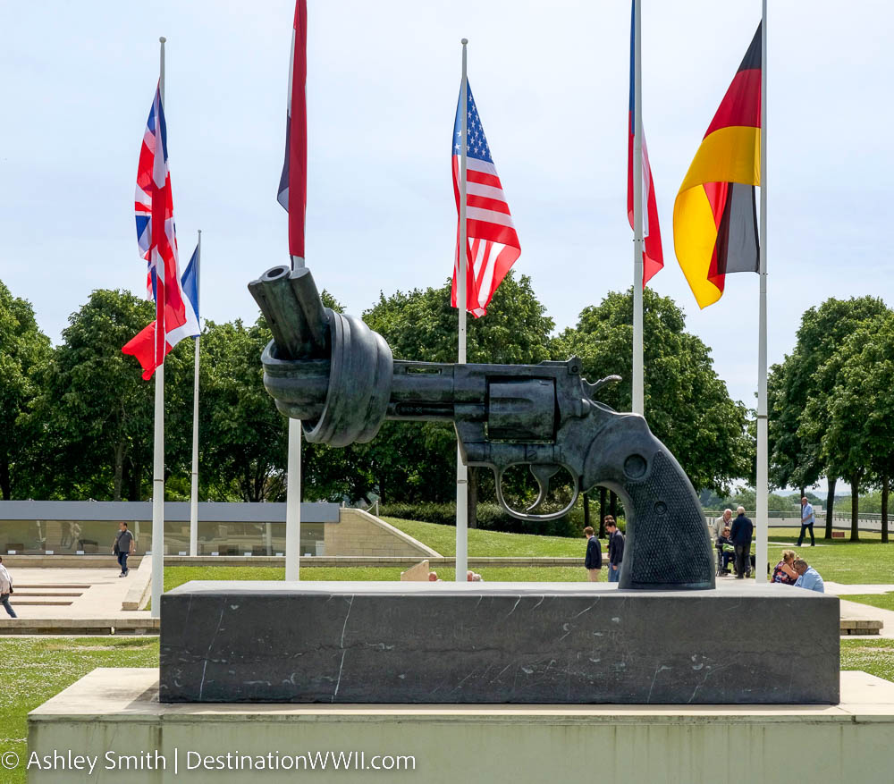 large non-violence sculpture in front of world flags