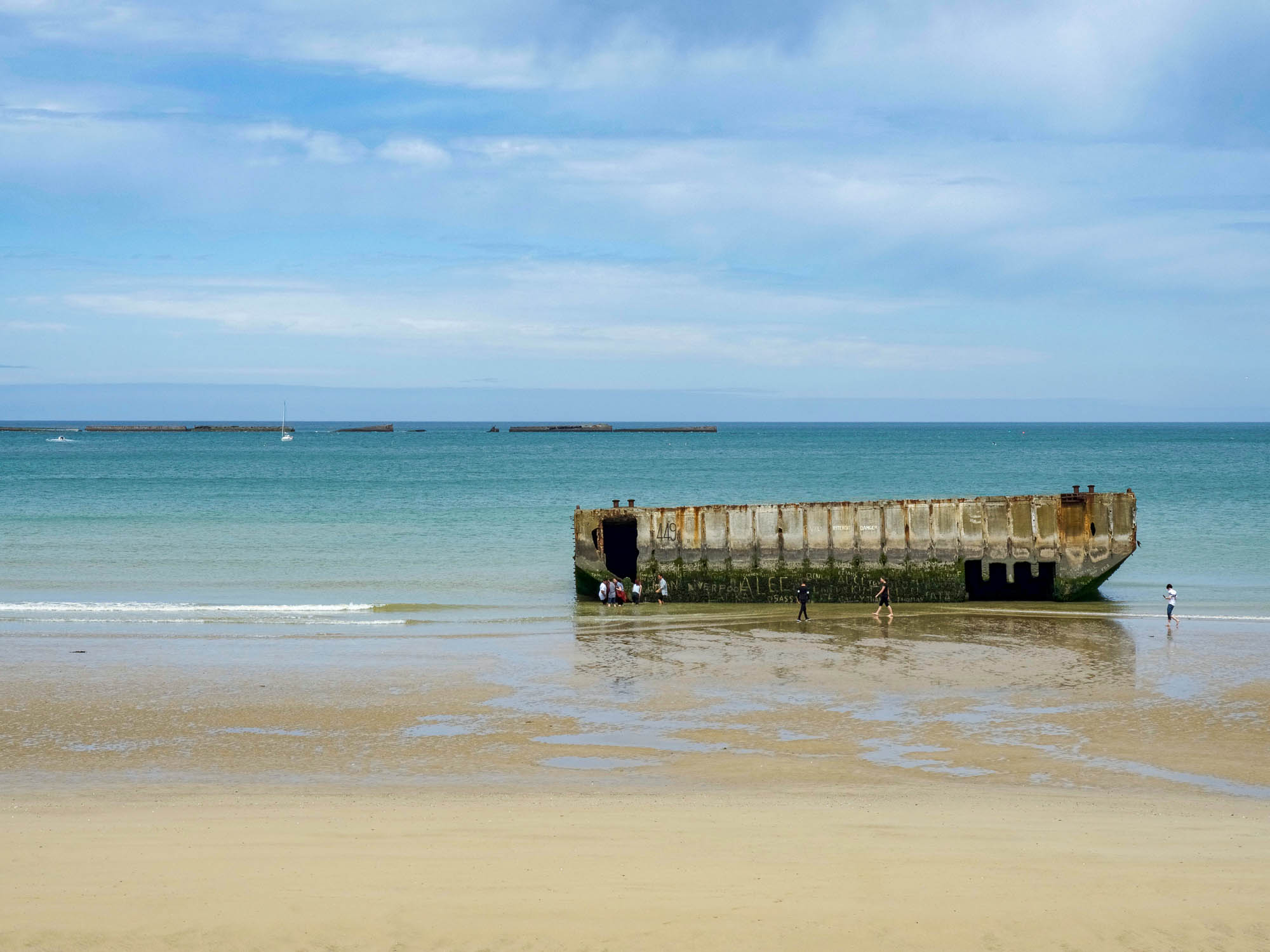 artifical harbor of arromanches sitting in a teal ocean