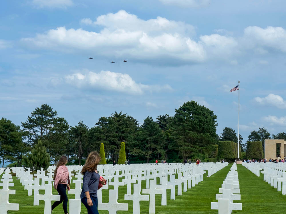 three jets flying over the marble crosses at normandy cemetery