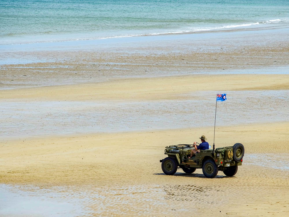 man in a wwii jeep on a beach