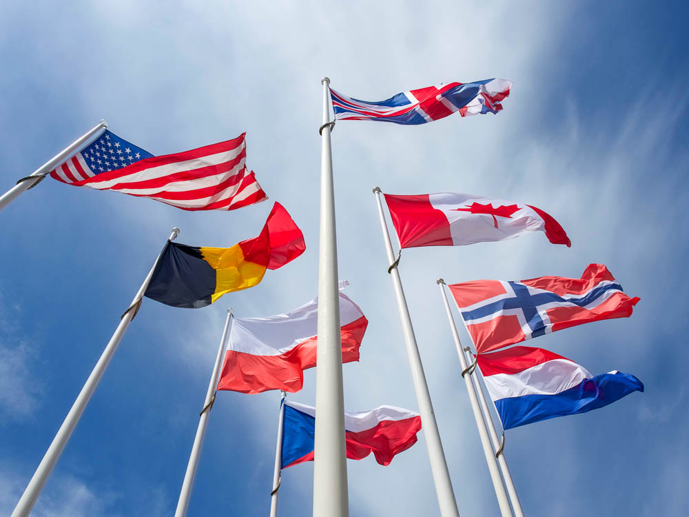 8 flags of many countries under a blue sky