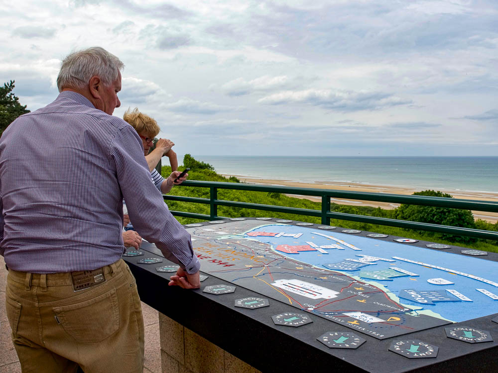 couple looking at a map of the d-day landing beaches next to the beach