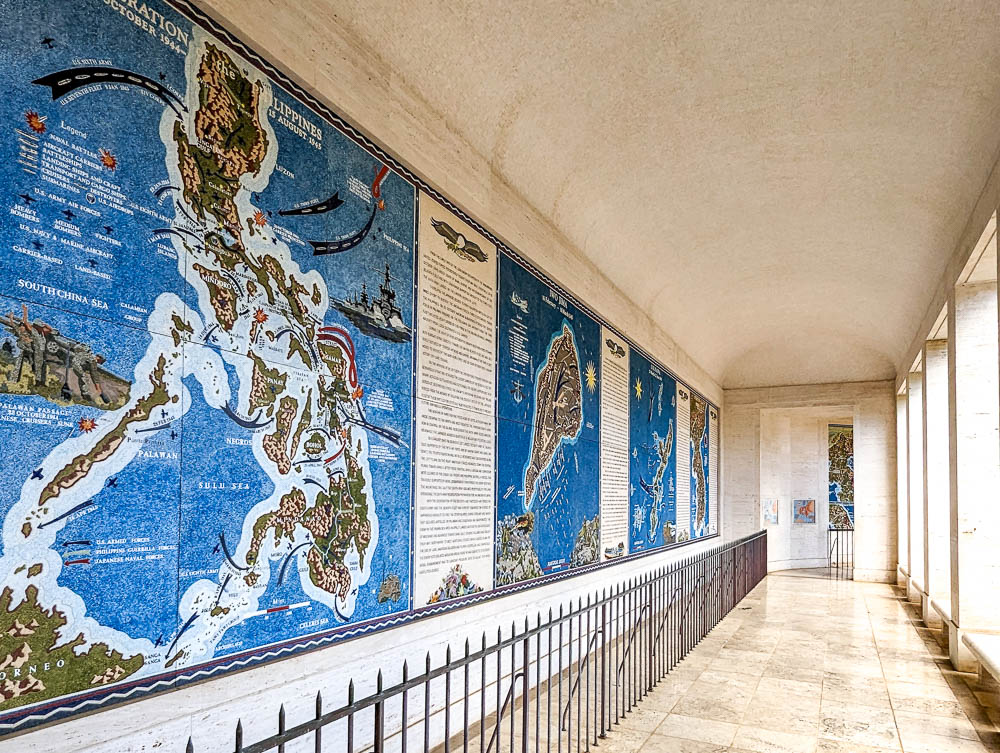 long hallway lined with brightly colored mosaics of pacific ocean battles at the punchbowl cemetery
