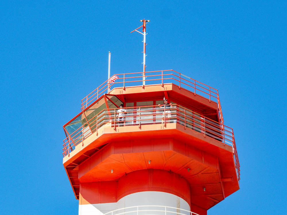 tall orange and white air control tower under a blue sky