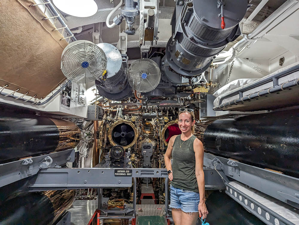 woman in a green shirt posing for a photo inside a submarine