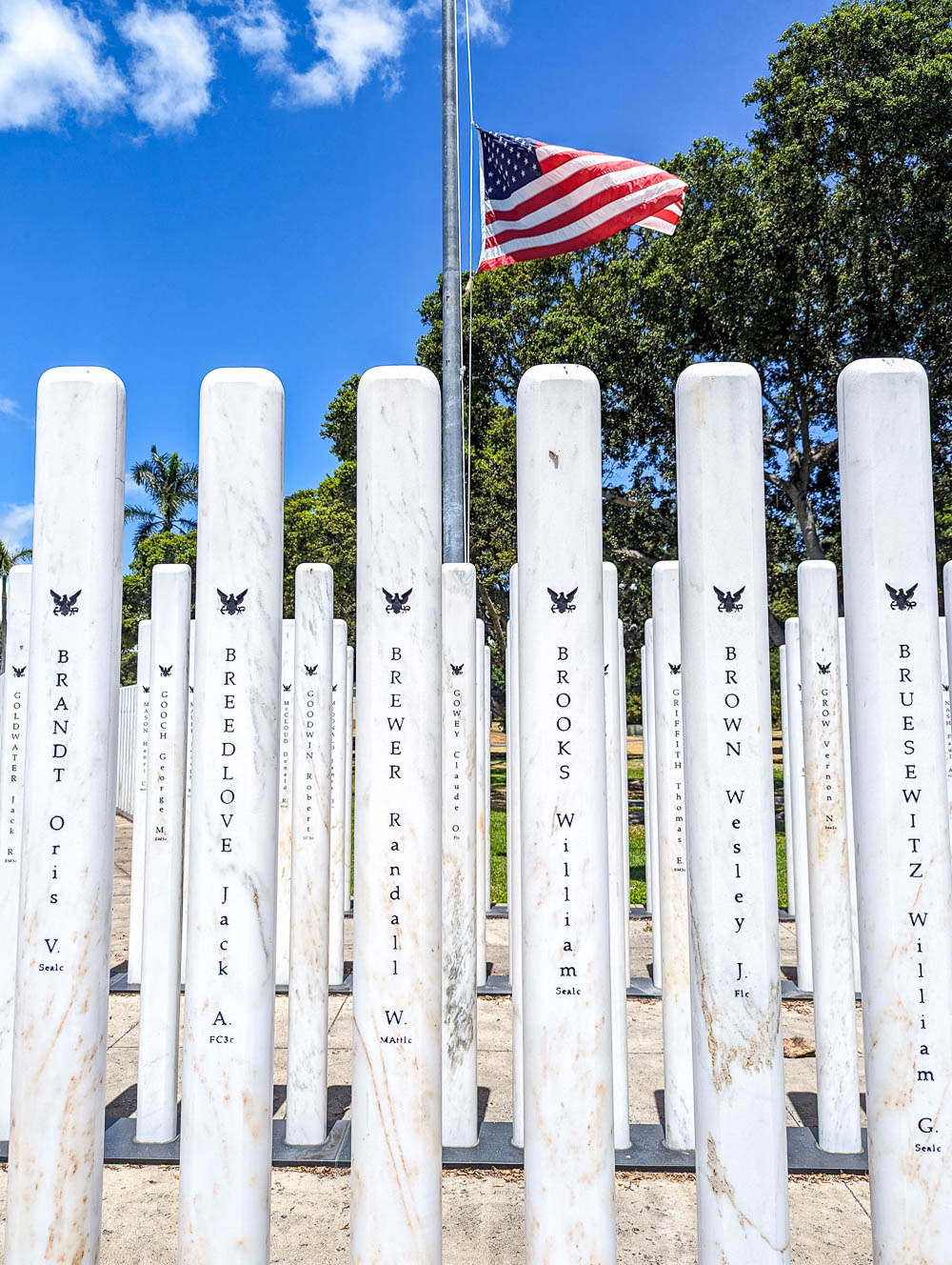 white pillars with names on them in front of an american flag on a pole