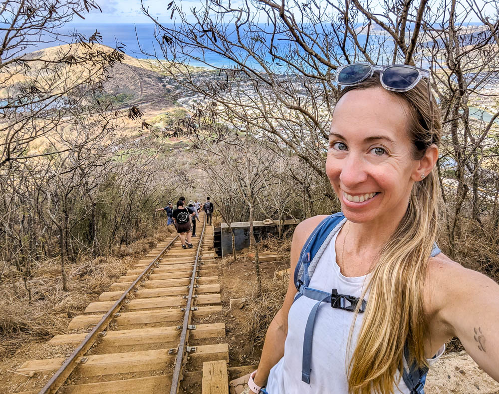 woman smiling next to a steep set of stairs on the side of a mountain