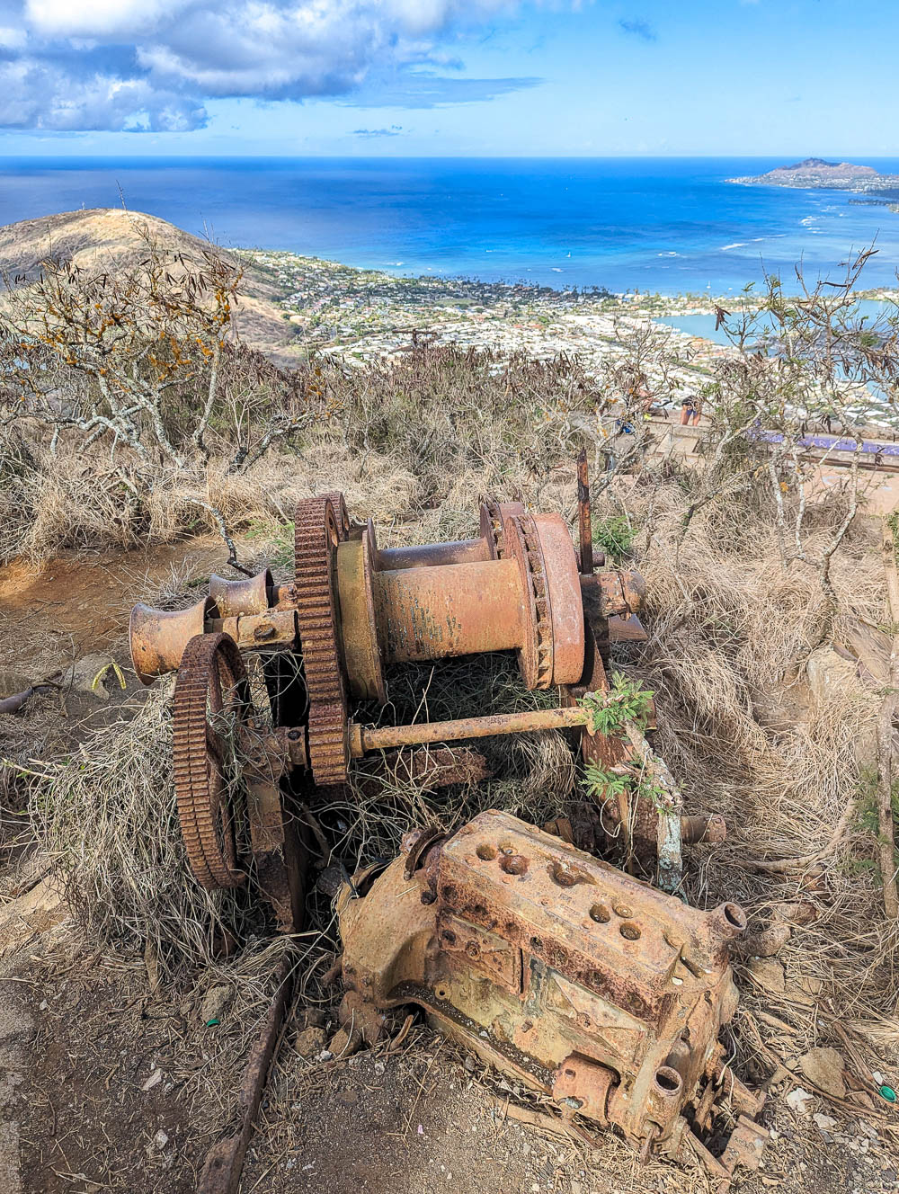 dirt hiking trail on the side of a mountain with rusty equipment strewn about