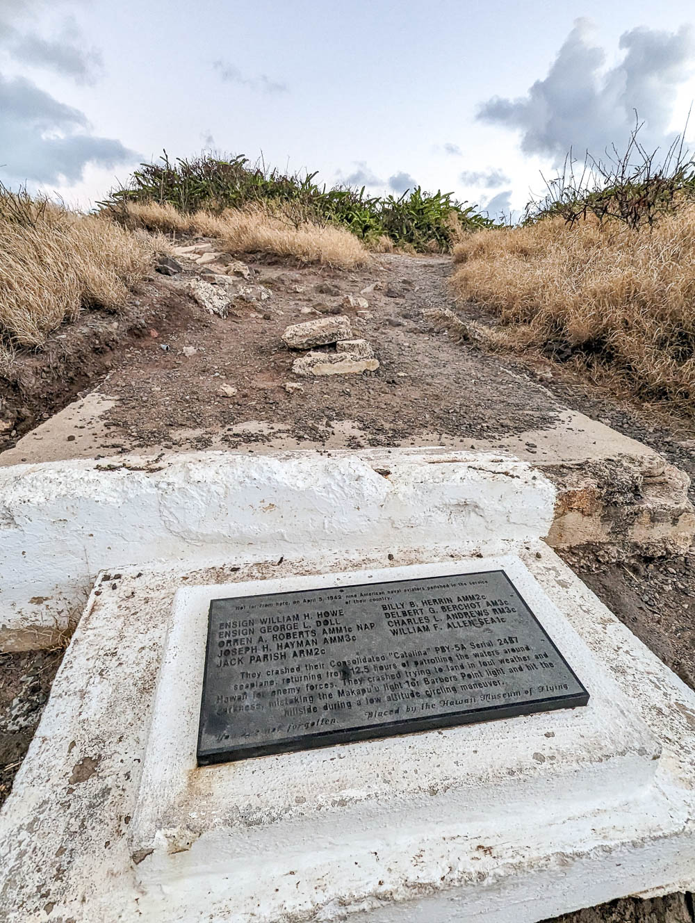 white stone memorial plaque surrounded by dirt and grass