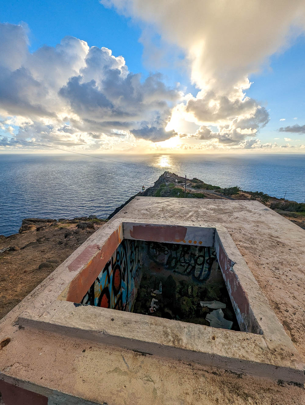 looking down into an old bunker on top of a mountain high above the ocean