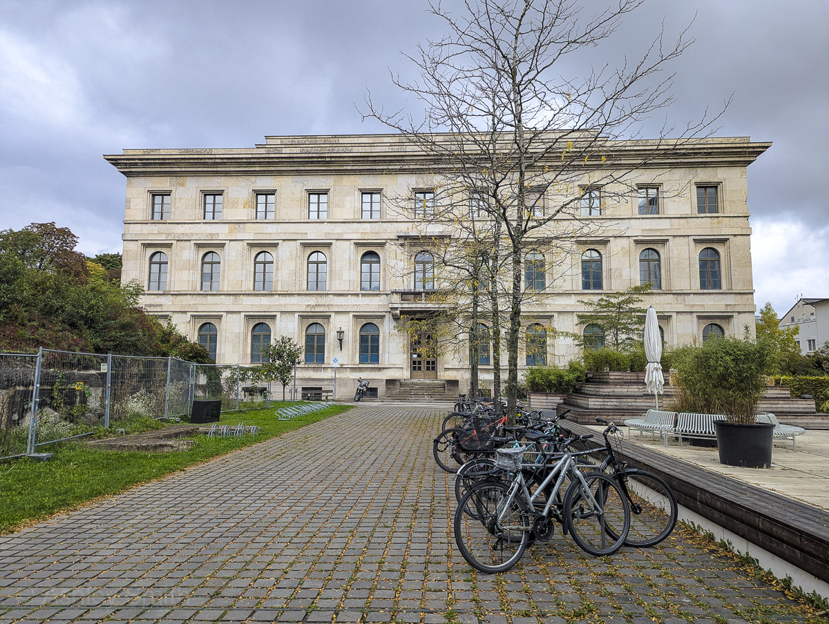 Block-shaped building at the end of a cobblestone walkway with bikes on it