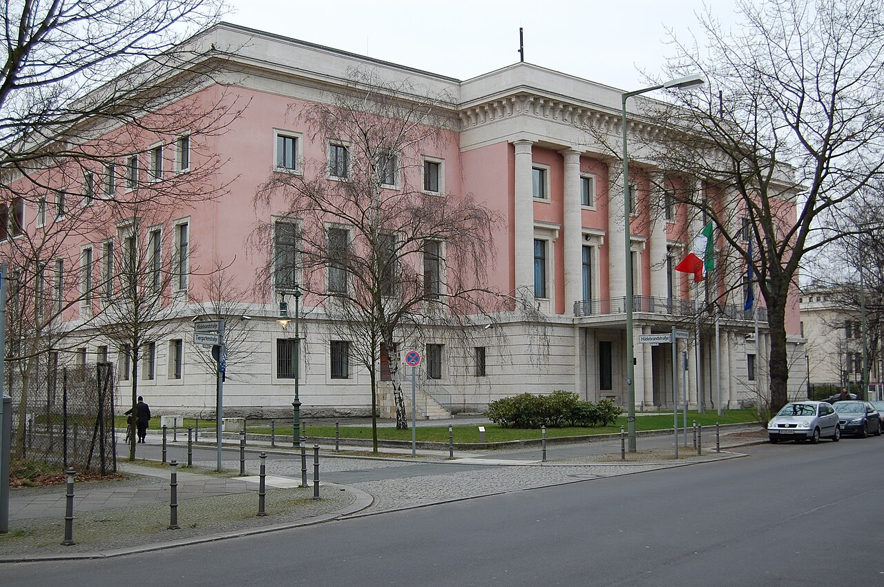 Pink block-shaped building surrounded by leafless trees in the winter