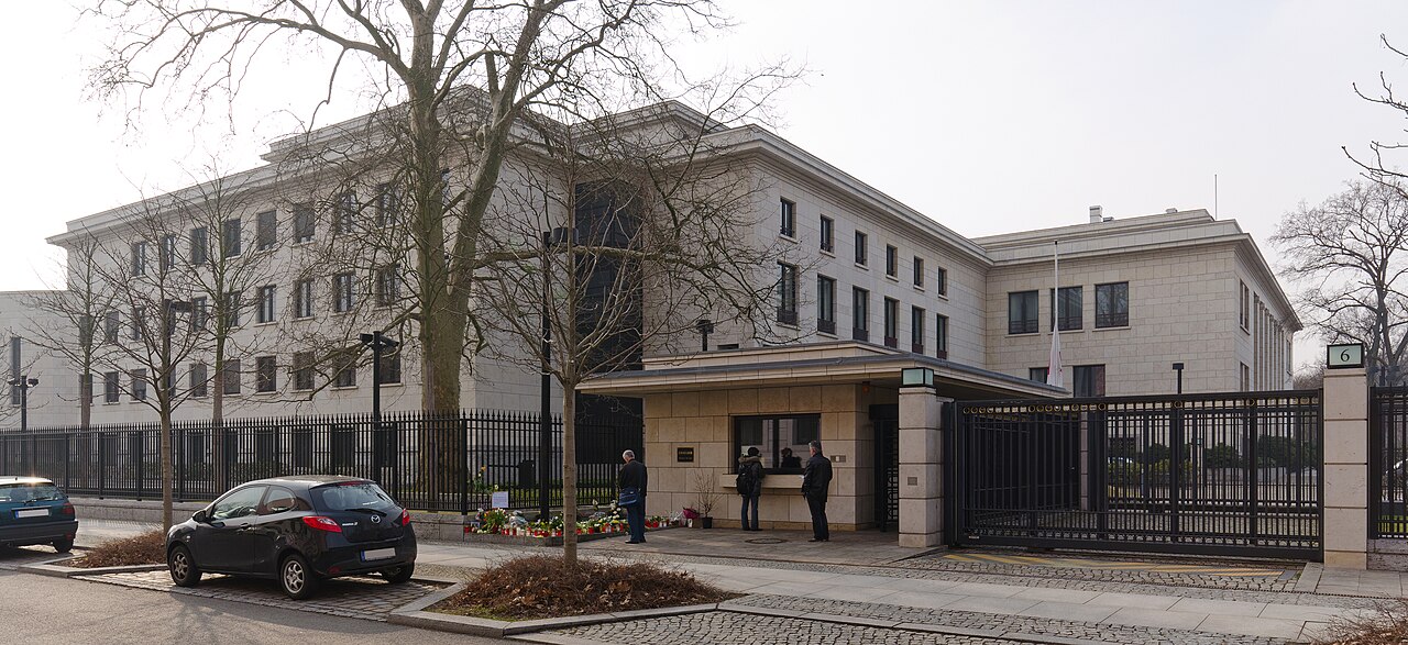 Beige block-shaped building surrounded by an iron gate