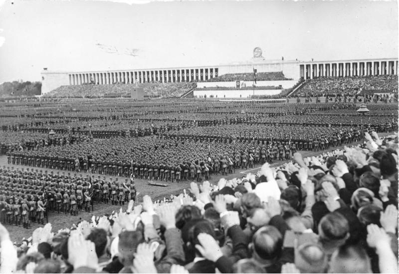 historical photo of a large grandstand behind tens of thousands of people