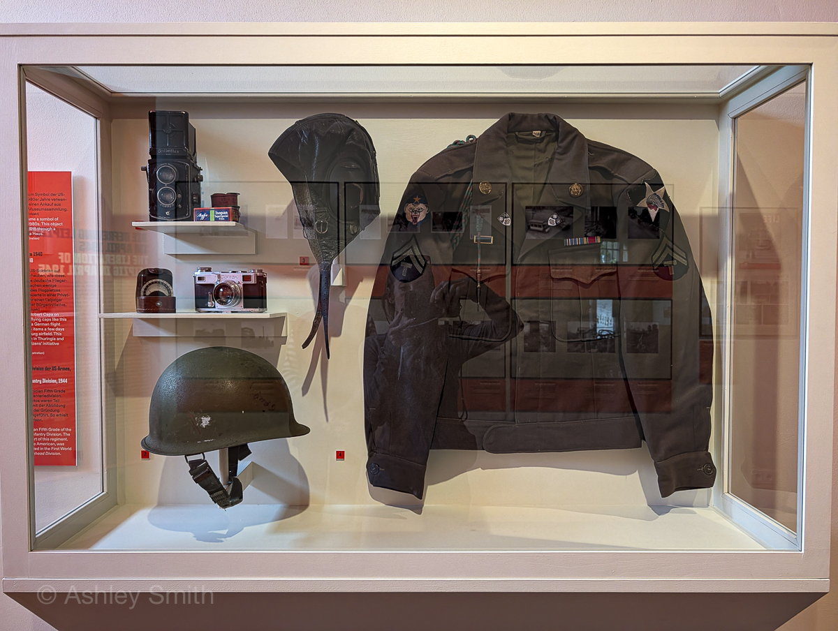 army jacket, helmet, and camera inside a display case