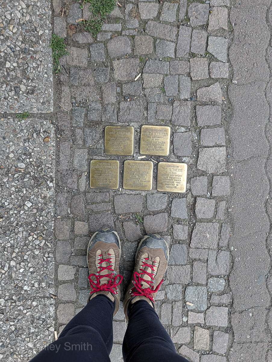 person standing over five brass cobblestones